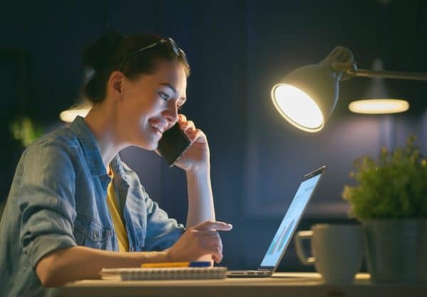 Woman working on laptop while talking on a mobile phone